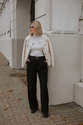 a lady in a white top, a beige outerwear and a pair of black pants